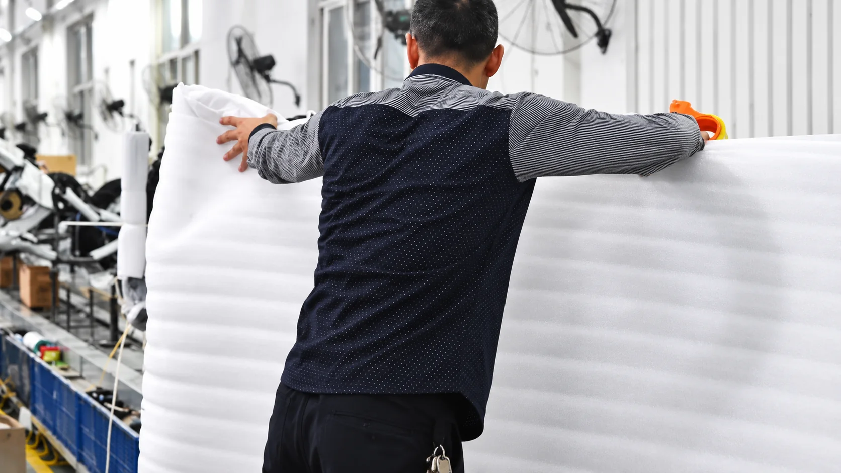 Worker handling a large sheet of protective foam at a packing station
